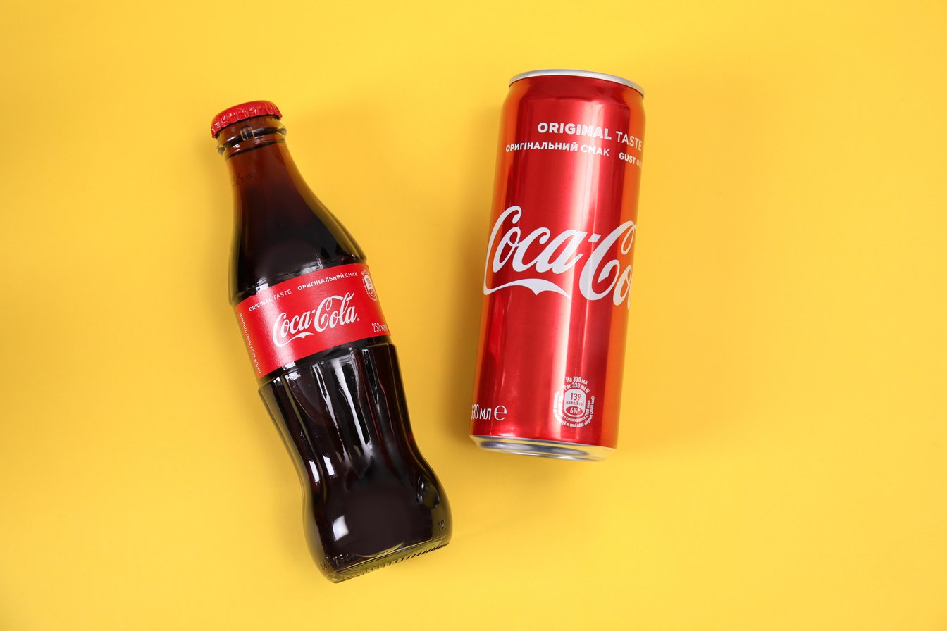 MYKOLAIV, UKRAINE - NOVEMBER 14, 2018: Can and Bottle of Coca-Cola on Color Background, Top View