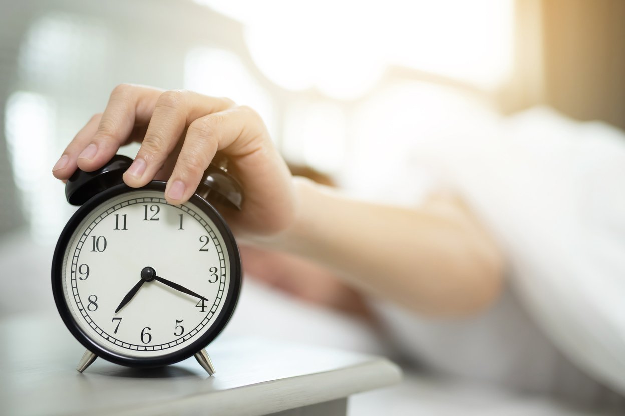 Female Hand Snoozing Alarm Clock in the Morning