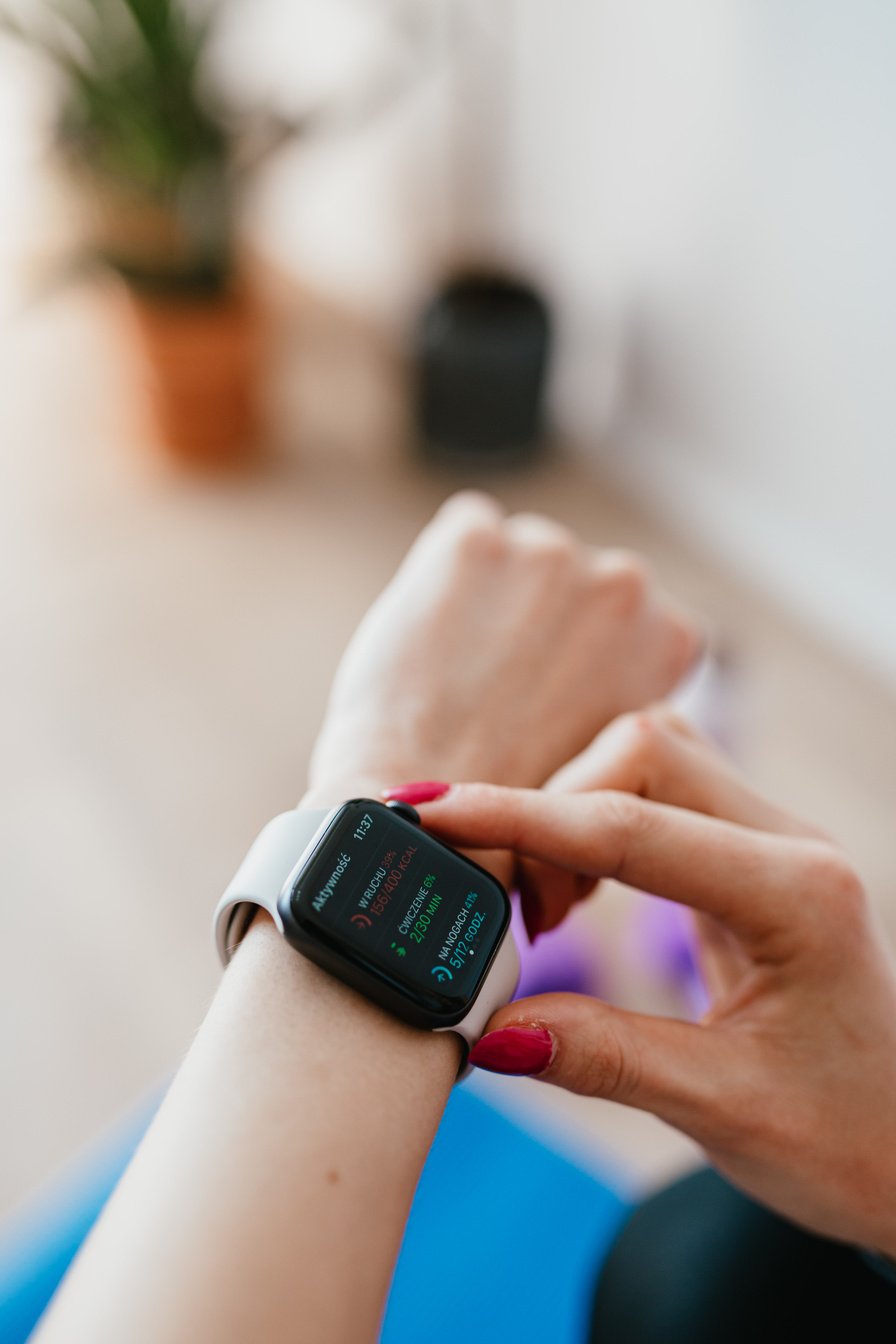 Crop woman using smart watch on yoga mat